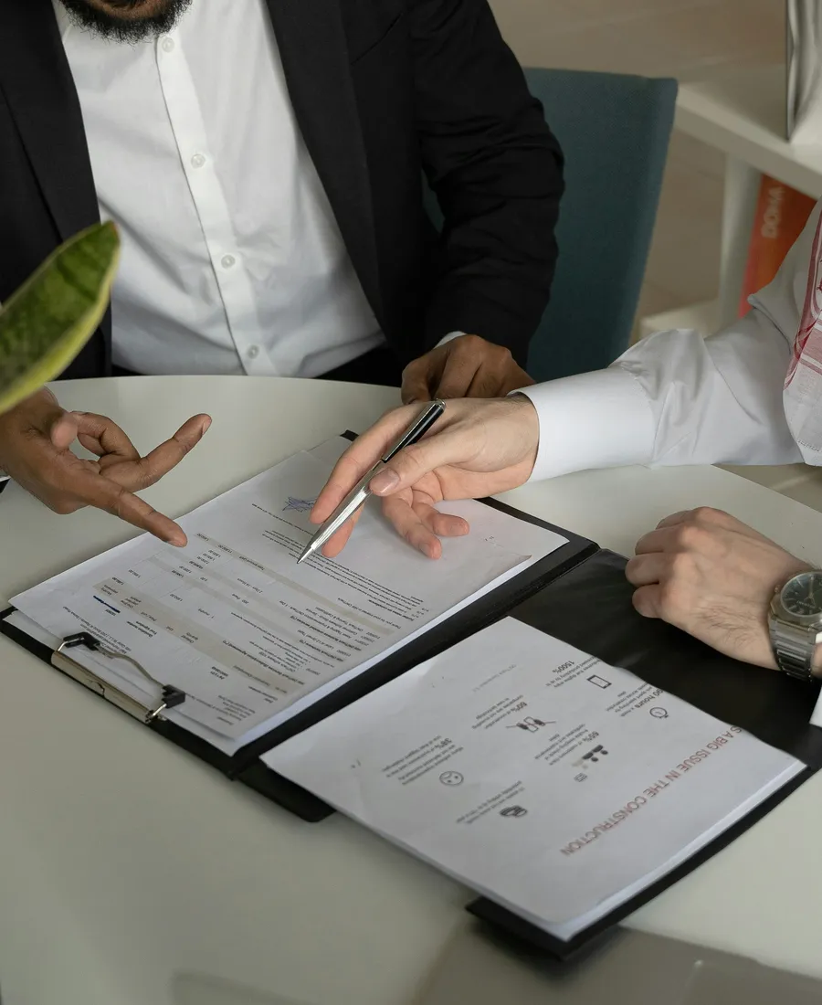 Due professionisti al tavolo con documenti e appunti durante una trattativa.